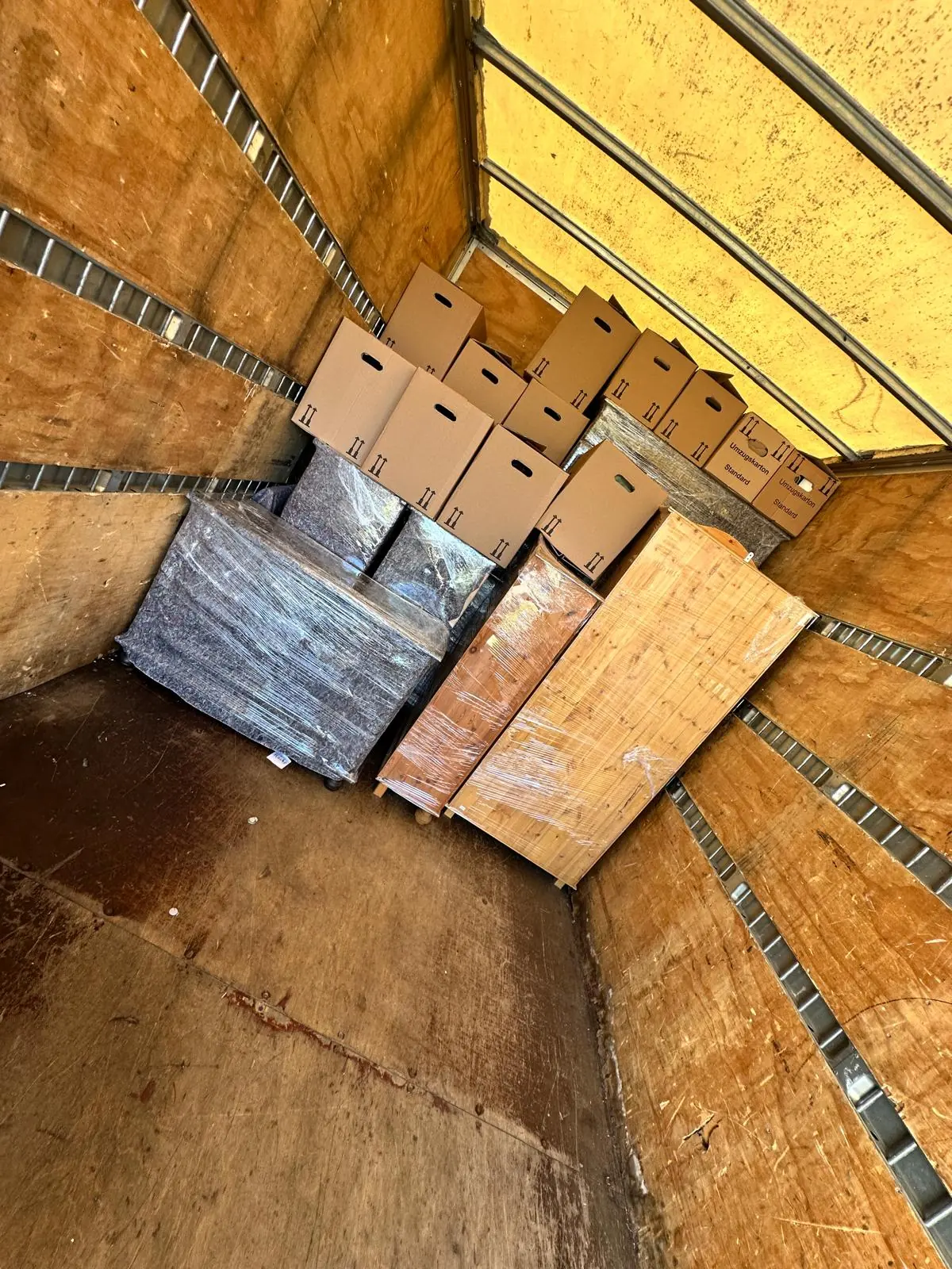 Kartons und verpackte Möbel einer Beiladung, gesichert im Laderaum