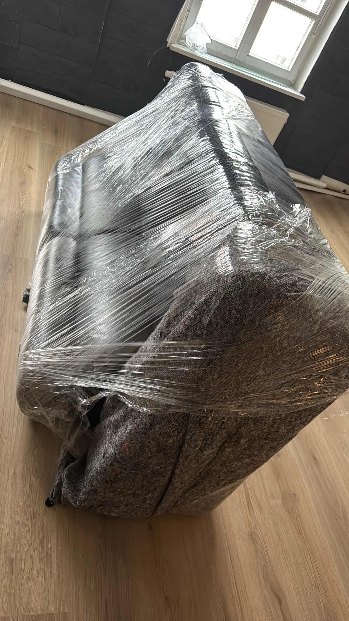 Sofa in Möbeldecke und Stretchfolie verpackt