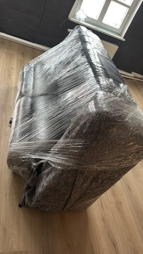 Sofa in Möbeldecke und Stretchfolie verpackt, bereit für den Transport