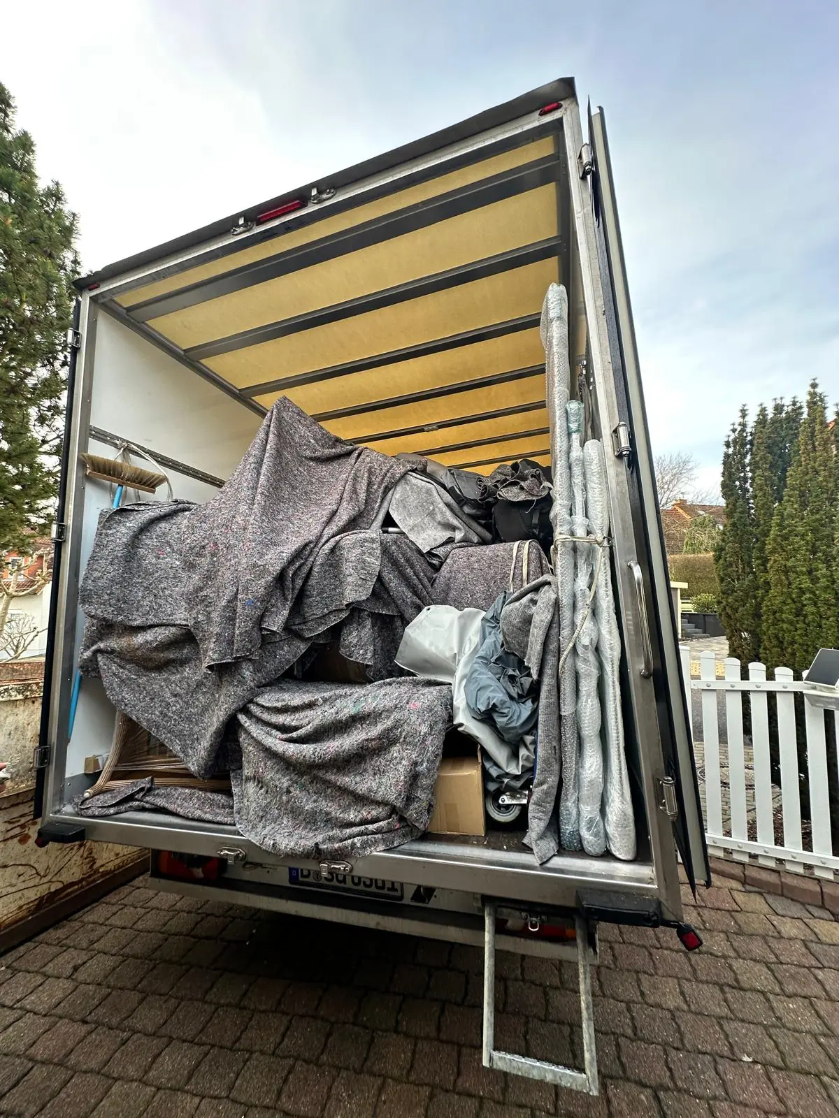 Voll beladener Umzugswagen mit in Decken geschützten Möbeln vor der Abfahrt