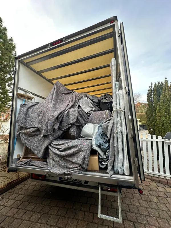 Voll beladener Umzugswagen mit in Decken geschützten Möbeln vor der Abfahrt